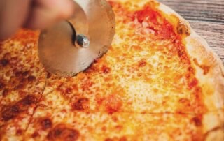 NY Style Pizza being cut