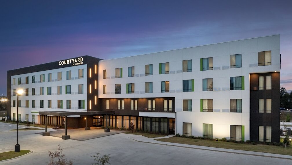 A modern Courtyard hotel at dusk, with a glowing entrance and surrounding landscaping in Northport, Alabama near The University of Alabama.
