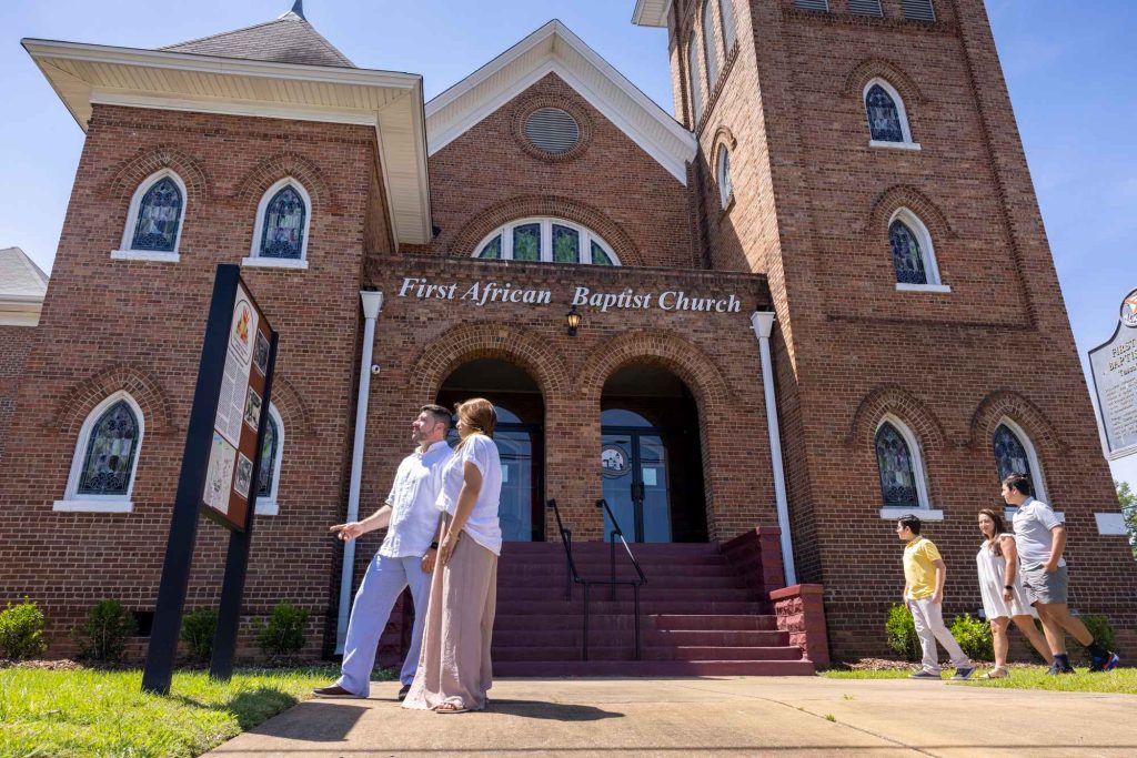 People reading a sign outside of the First African Baptist Church