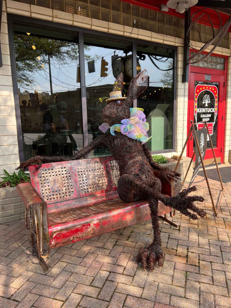 A sculpture of a humanoid bunny sitting on the bench you could take a photo with.