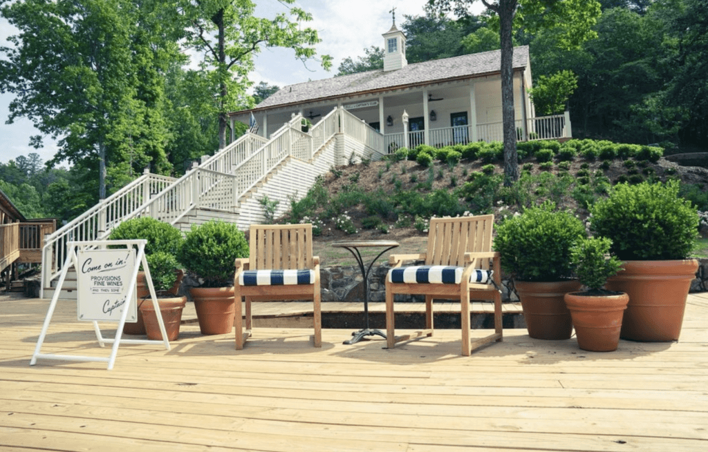 A charming wooden deck with striped cushions, potted plants, and a sign inviting visitors to 'Come On In!'