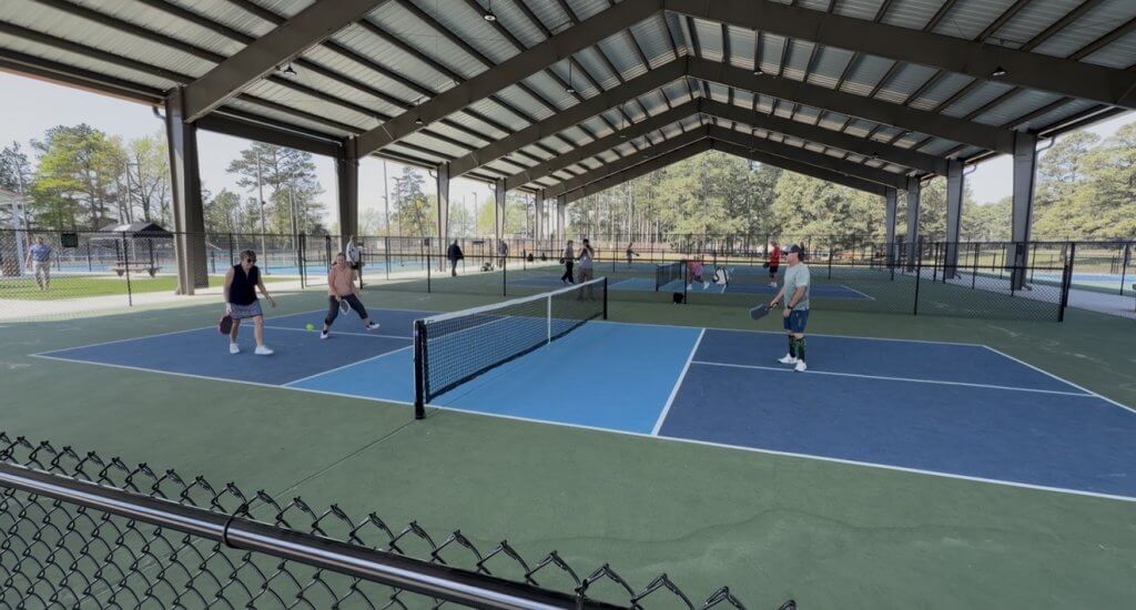 A group of people playing tennis on a covered court in Tuscaloosa, Alabama.