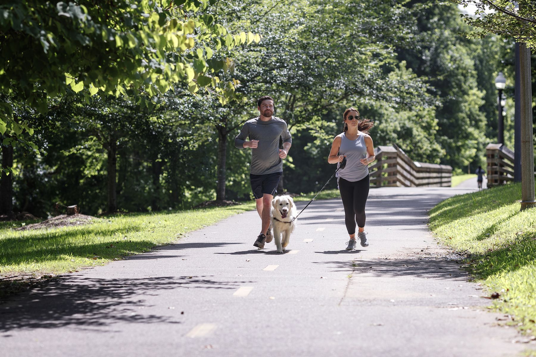 Couple jogging with their dog along the Tuscaloosa Riverwalk, a scenic spot to enjoy an outdoors long weekend.