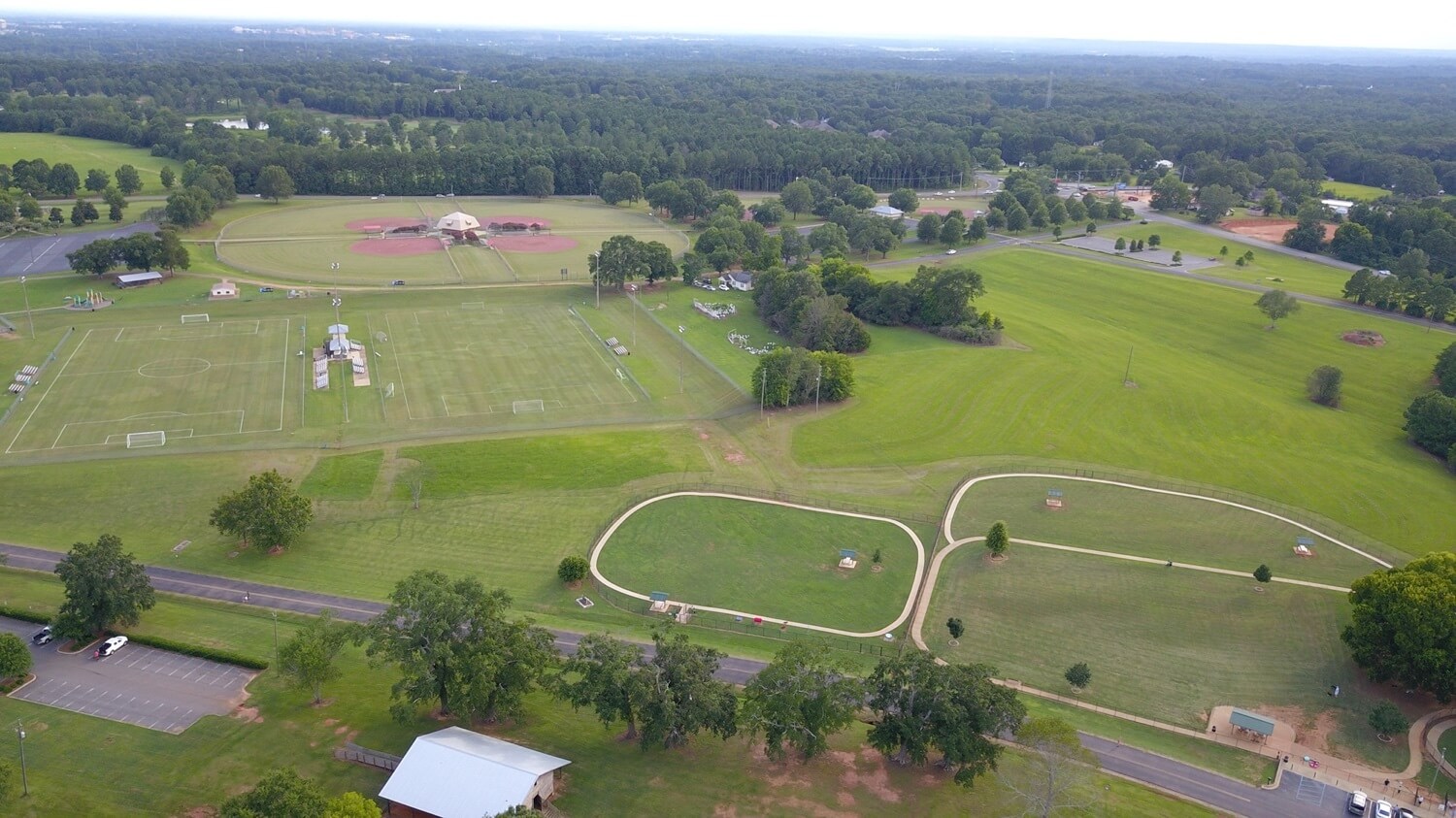 A sprawling park with sports fields, walking paths, and picnic areas surrounded by lush greenery in Tuscaloosa, Alabama.