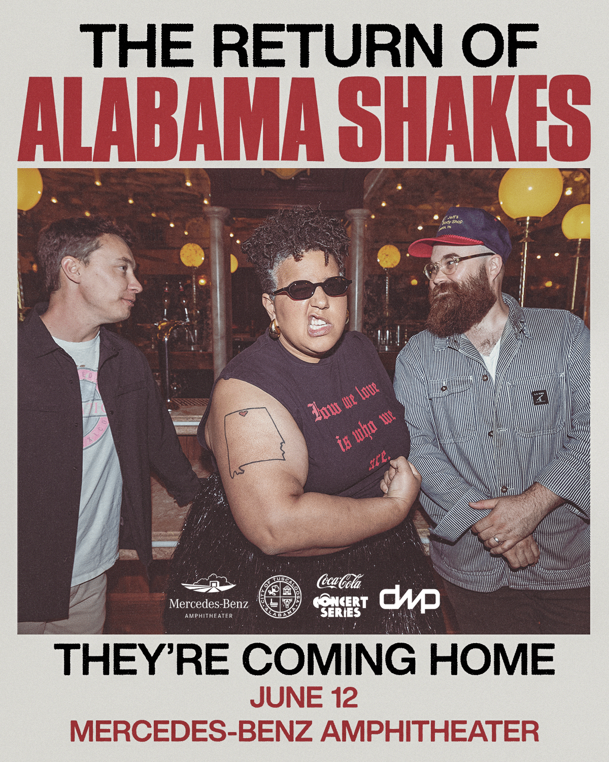 Three musicians, including a woman with a beard and a man with a beard, are posing together on a stage with a backdrop that reads 'The Return of Alabama Shakes'. They are dressed in casual attire and appear to be smiling in Tuscaloosa, Alabama.