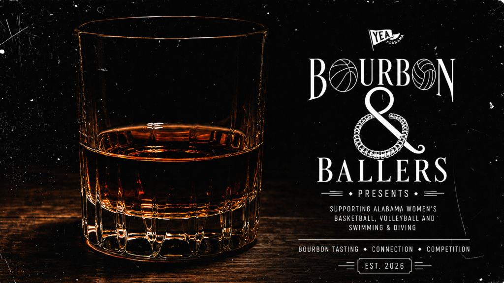 A glass of bourbon whiskey sits on a wooden table, with a poster advertising 'Bourbon & Ballers' supporting Alabama women's basketball, volleyball, swimming, and diving in Tuscaloosa, Alabama.
