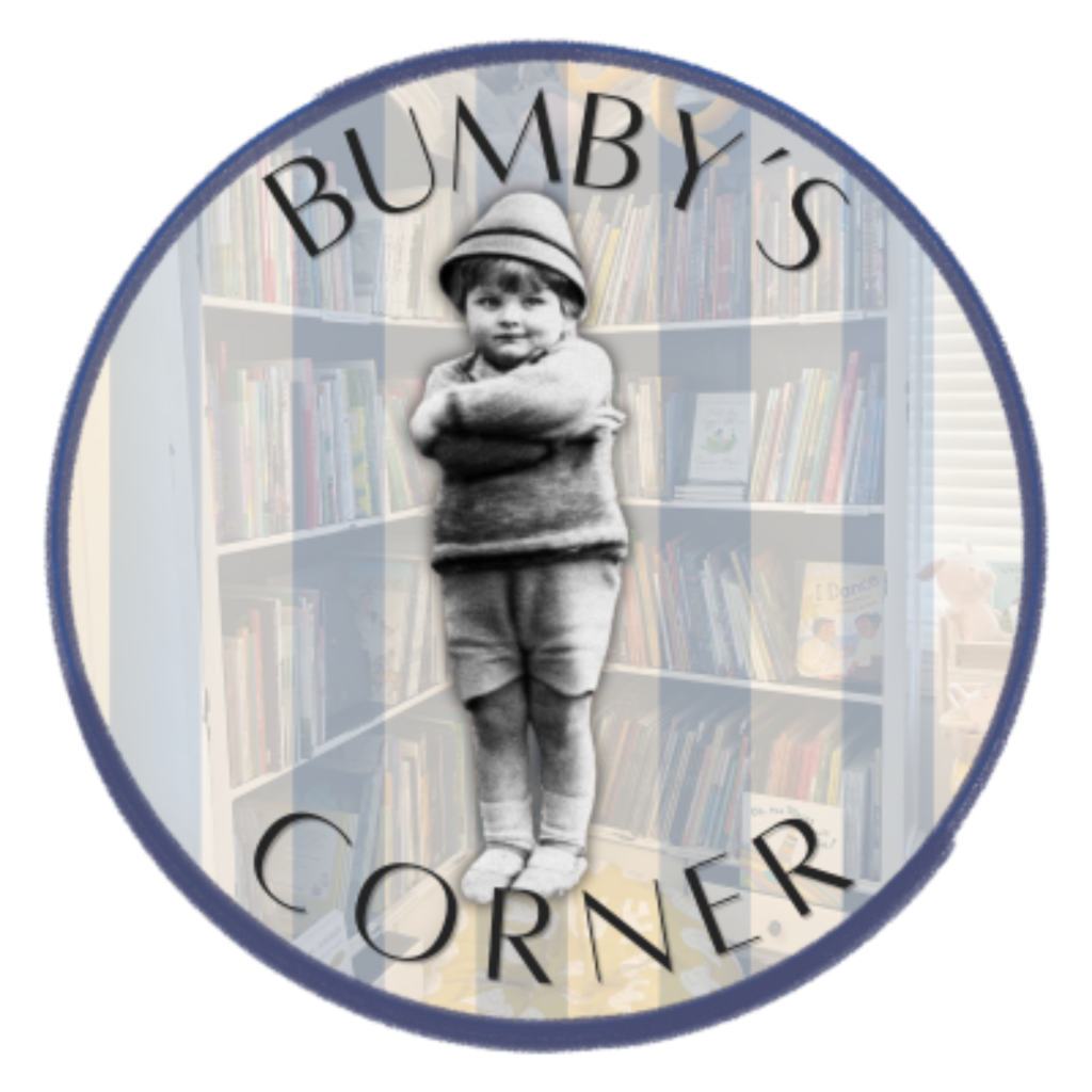 A young child stands confidently in a library, arms crossed, surrounded by bookshelves in Tuscaloosa, Alabama.