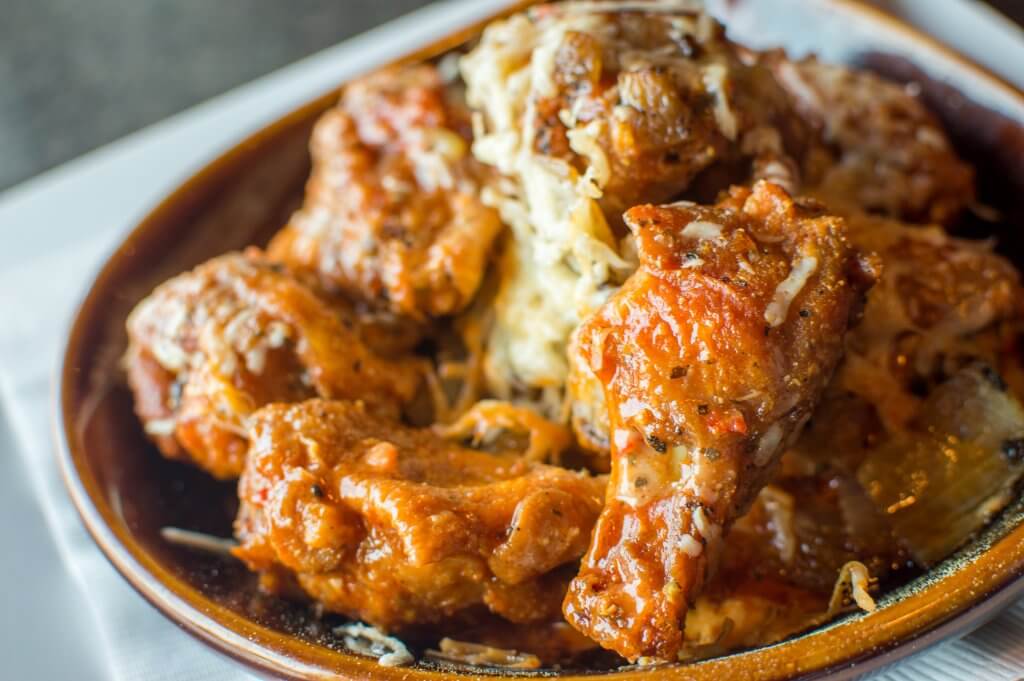 A bowl of buffalo chicken wings covered in melted cheese and served with a side of ranch dressing in Tuscaloosa, Alabama.