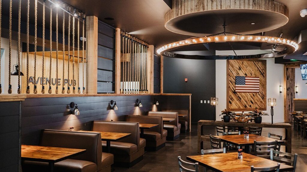 A modern restaurant interior with rustic elements, featuring brown leather booths, wooden tables, and a circular light fixture in Tuscaloosa, Alabama.