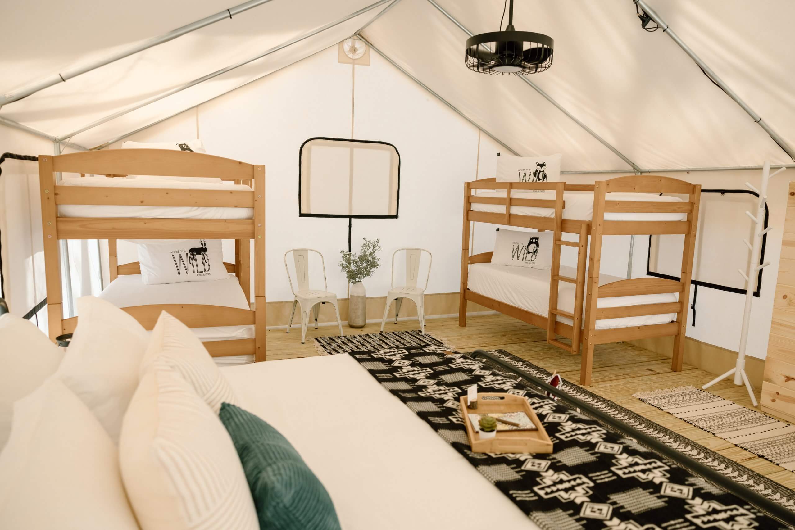 A cozy glamping tent with four wooden bunk beds, a large bed, and rustic decor in Tuscaloosa, Alabama.