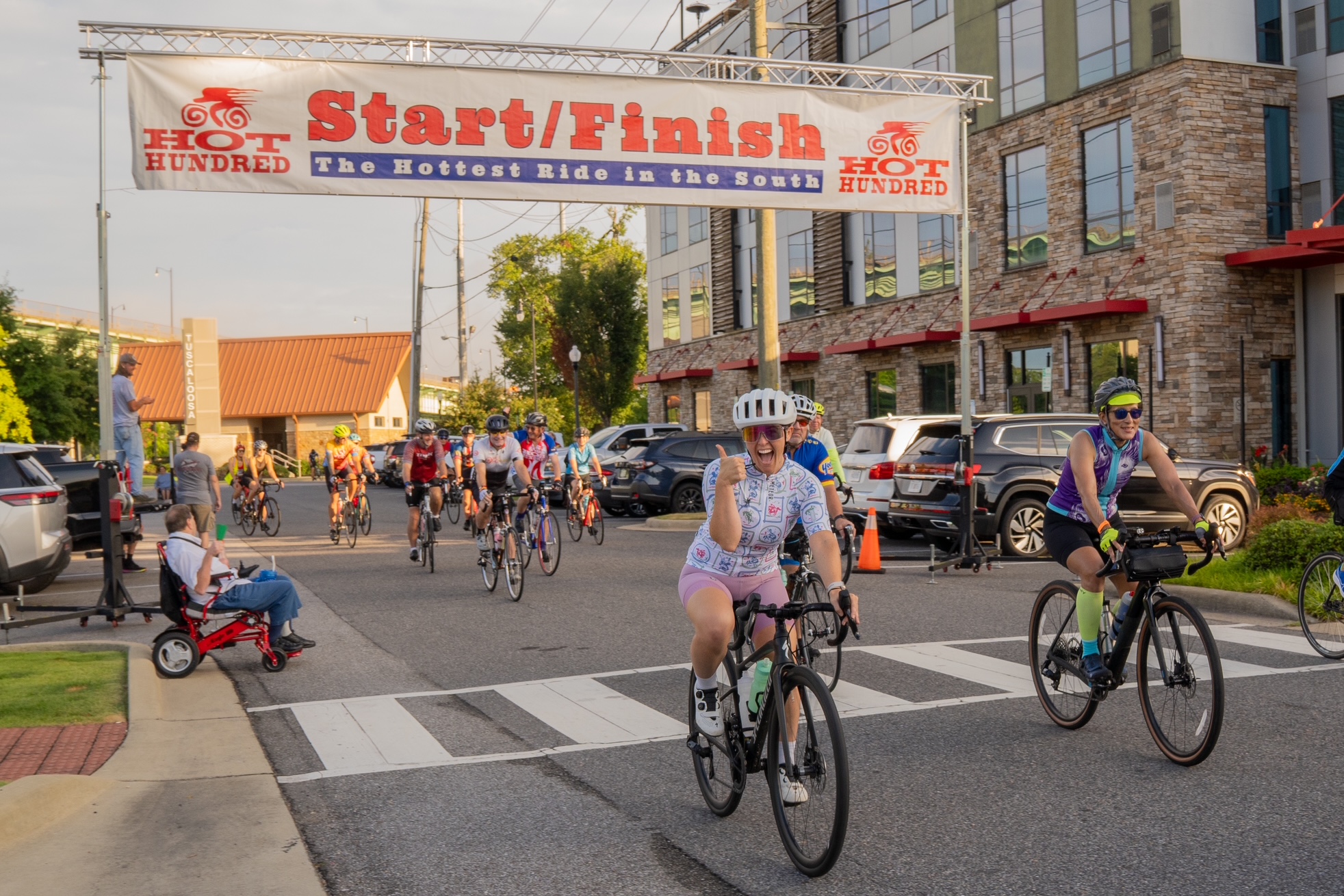 Cyclists cross the finish line of the Hot Hundred bike race, celebrating their achievement in Tuscaloosa, Alabama.