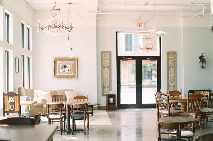 A spacious, well-lit room with a mix of wooden and upholstered furniture, chandeliers, and large windows in Tuscaloosa, Alabama.
