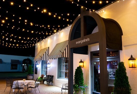 An elegant outdoor dining area at night, illuminated by string lights above a restaurant entrance in Tuscaloosa, Alabama.