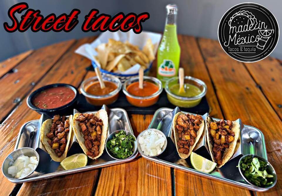 Two trays of street tacos with various toppings and sauces, accompanied by chips and a green soda bottle in Tuscaloosa, Alabama.