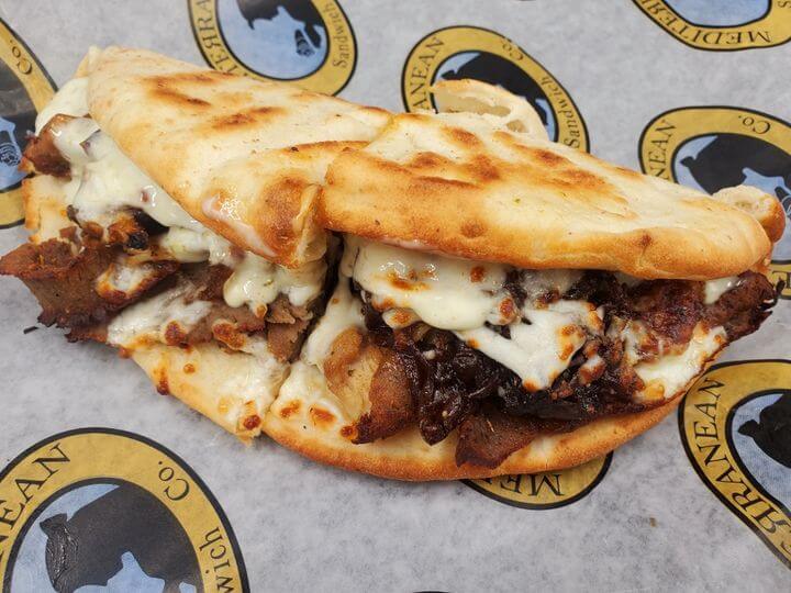 A mouthwatering Mediterranean-style sandwich with grilled pita bread, melted cheese, and savory meat filling in Tuscaloosa, Alabama.