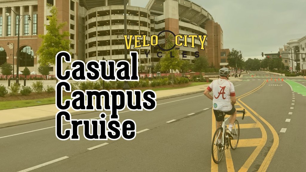 A cyclist wearing an Alabama jersey rides on a road near a large stadium in Tuscaloosa, Alabama.