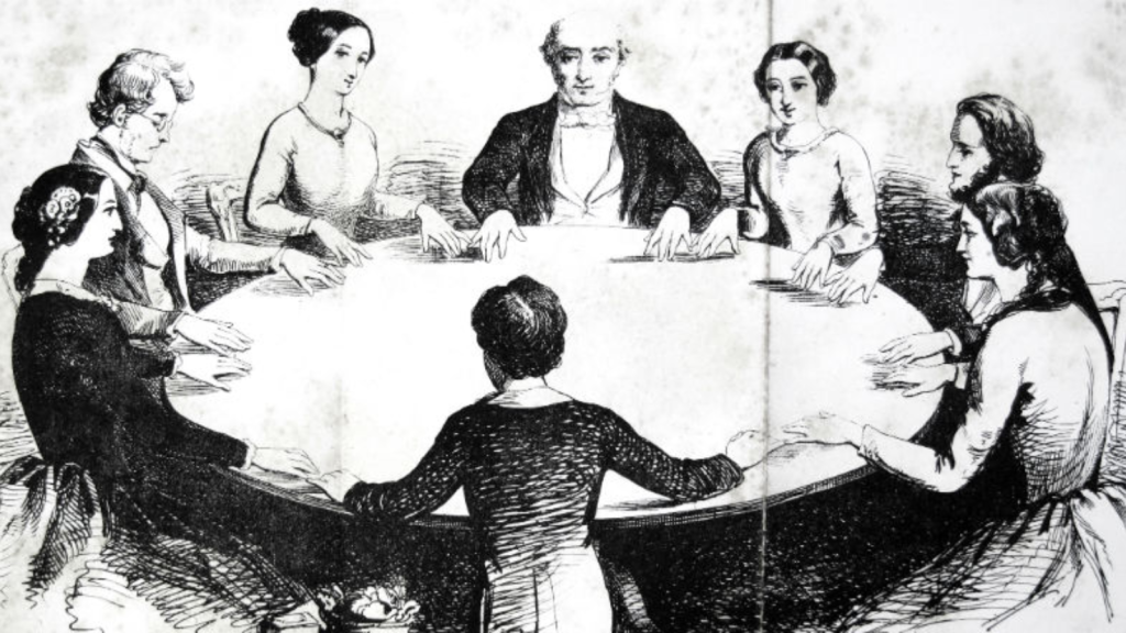 A group of people sitting around a round table participating in a seance in Tuscaloosa, Alabama.