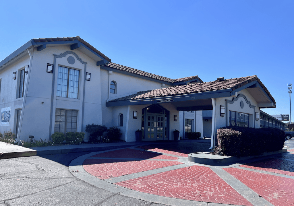 A hotel exterior with a red patterned driveway and a blue sky in Tuscaloosa, Alabama.
